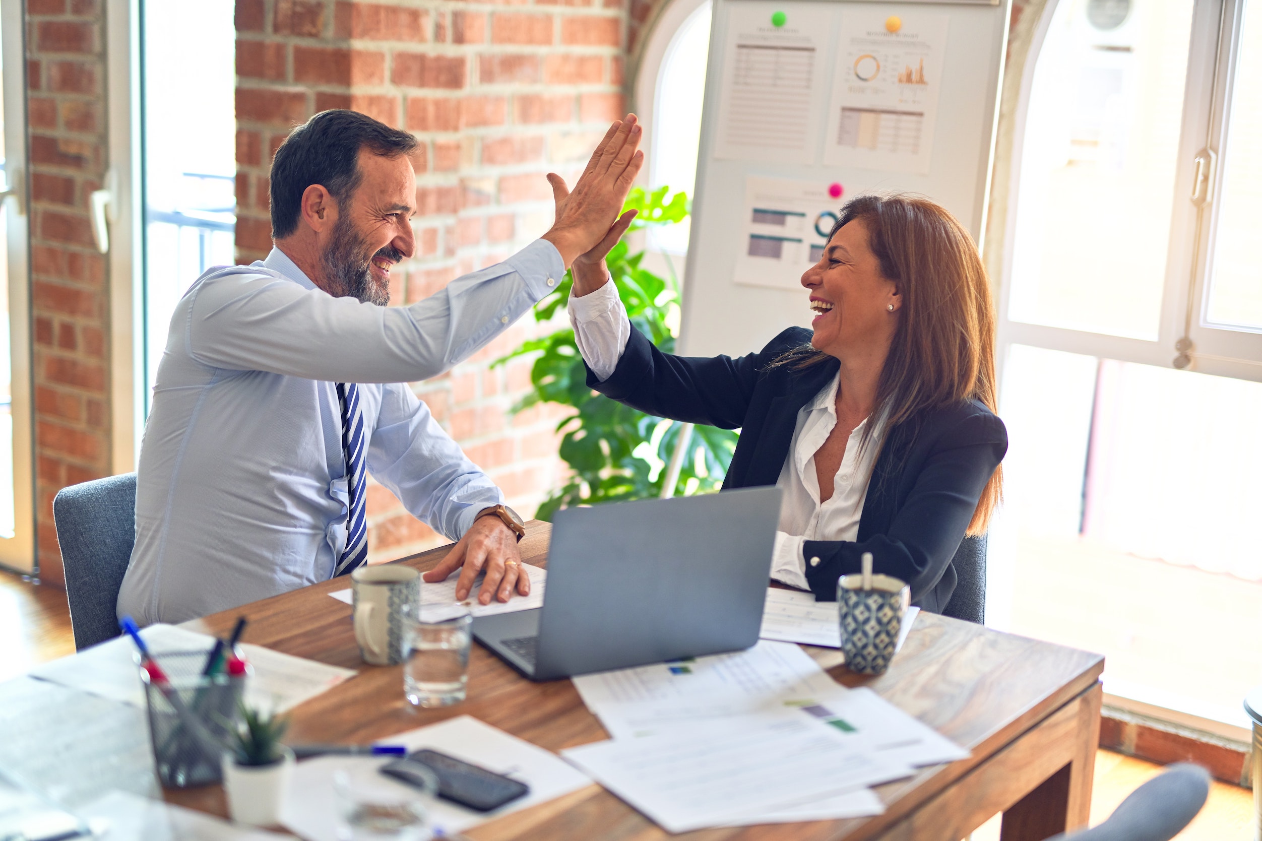 Businesswoman and businessman high-fiving each other